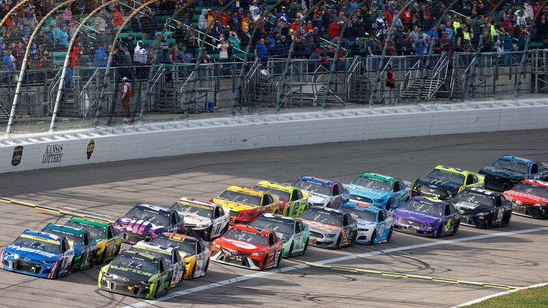 FILE - Drivers cross the start/finish line during a restart in a NASCAR Cup Series auto race...