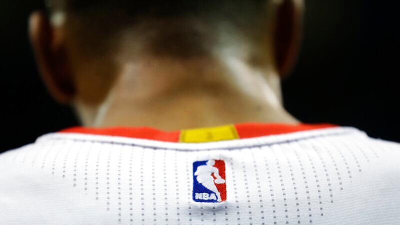 FILE - In this April 7, 2015 file photo, an NBA logo is displayed on the back of a player's...
