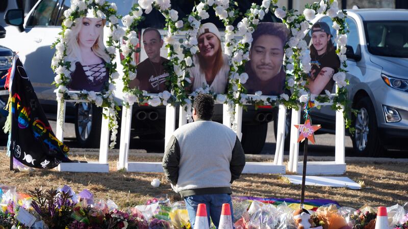 A person pauses to pay respects as portraits of the victims of a mass shooting at a gay...